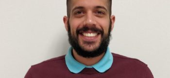 Ali Nadimi headshot wearing a light blue polo underneath a maroon sweater.