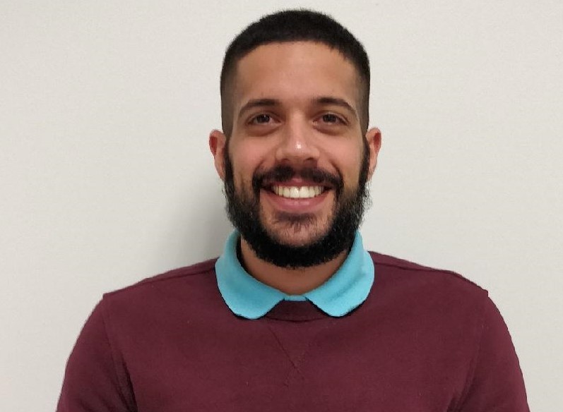 Ali Nadimi headshot wearing a light blue polo underneath a maroon sweater.