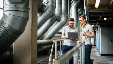 Two engineers with laptop in large printery