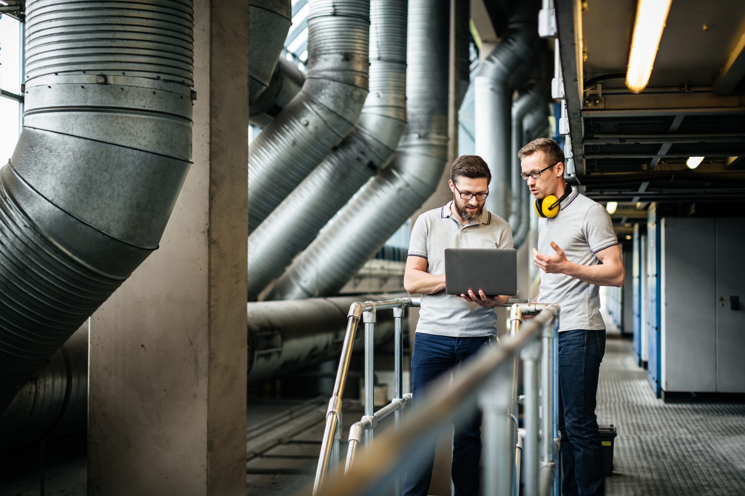 Two engineers with laptop in large printery