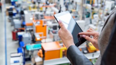 A woman using a smart tablet to manage a factory.