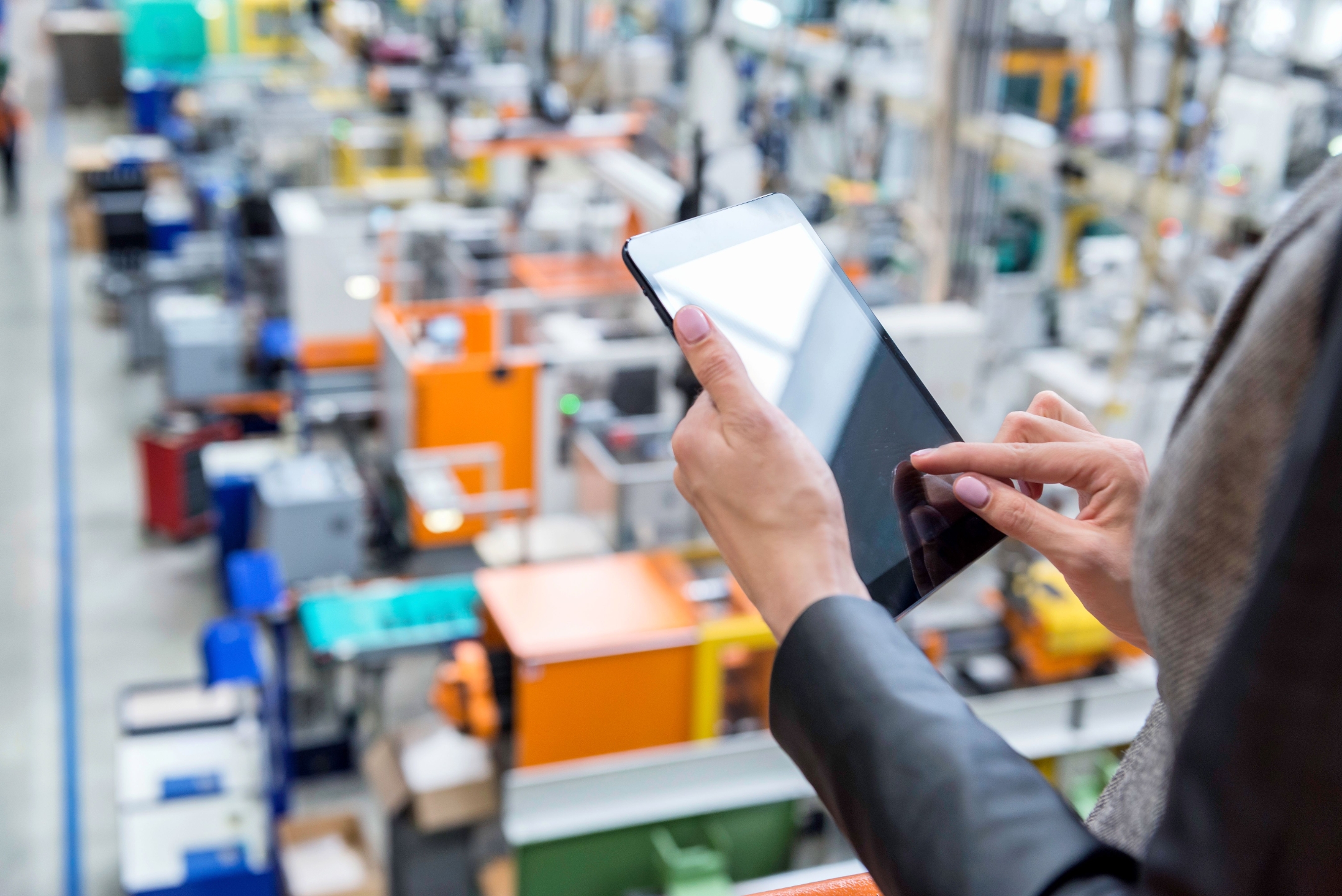 A woman using a smart tablet to manage a factory.