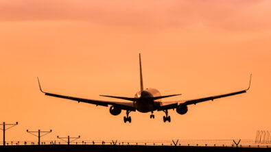 AN airplane taking off under an orange sky.