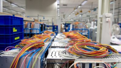 Spools of colored wires across tables in a factory.