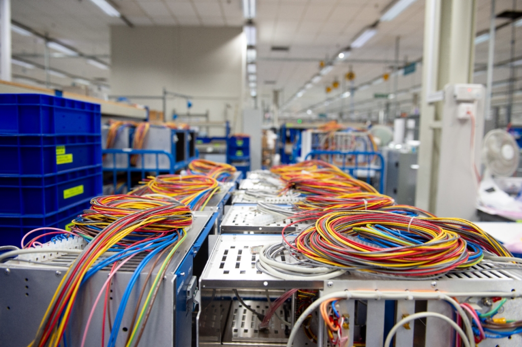 Spools of colored wires across tables in a factory.