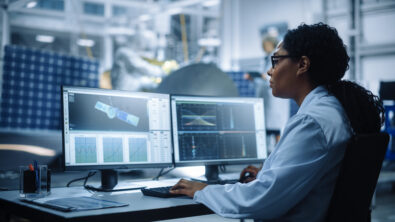 An engineer analyzing a space satellite on a computer.