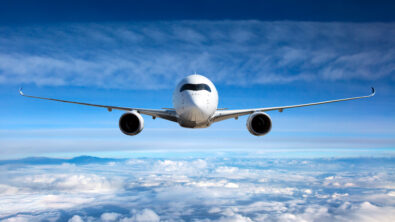 Front view of a commercial airplane flying above the clouds.