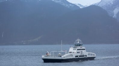 A medium-sized ship sailing along a mountainous coast.