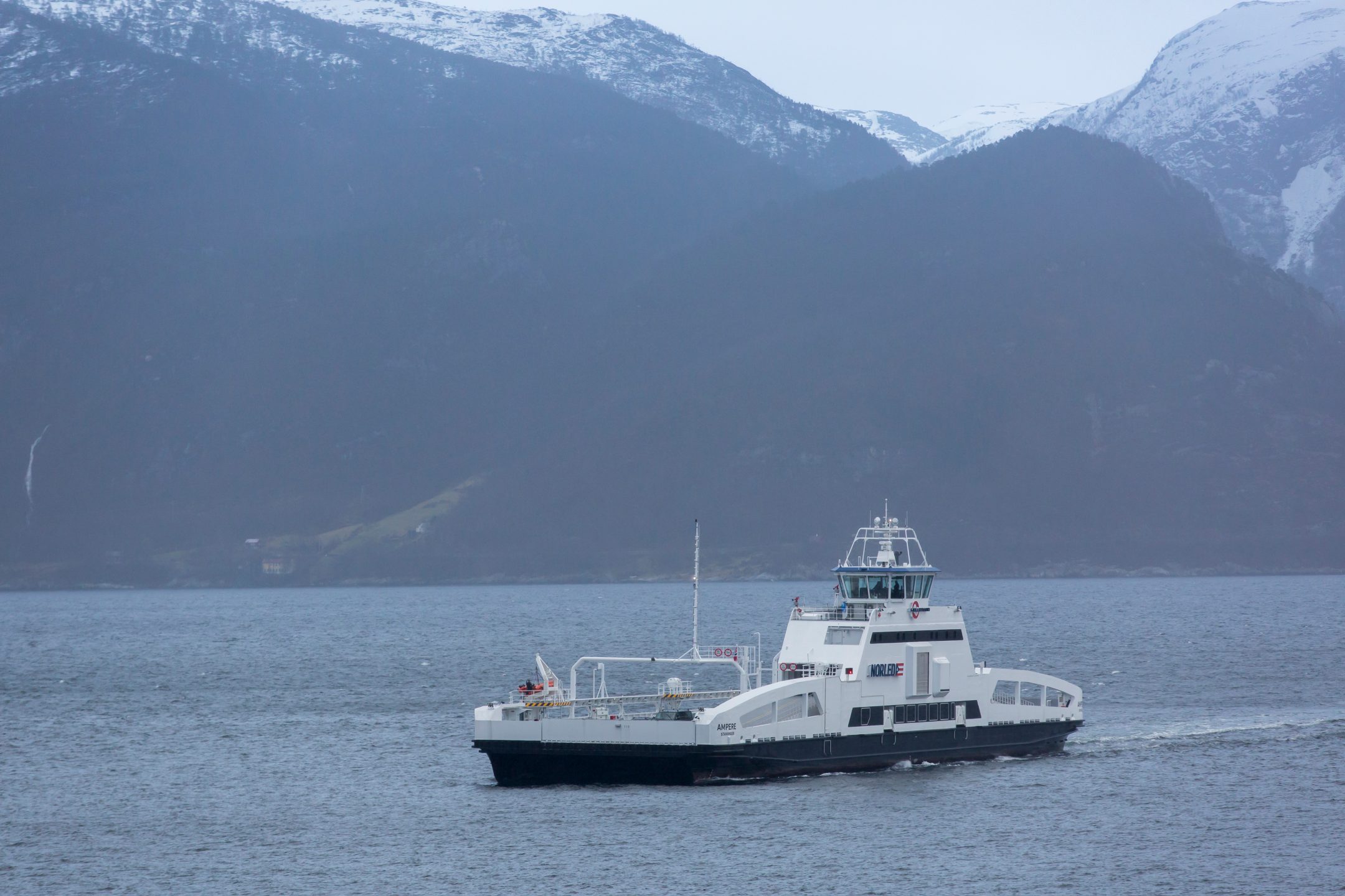 A medium-sized ship sailing along a mountainous coast.