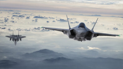 Two fighter jets flying above a mountainous landscape.