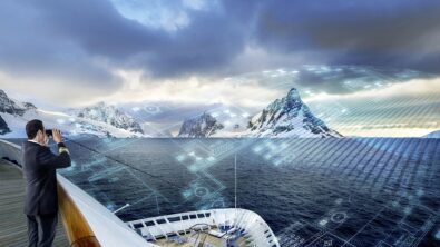 A man with a tablet looking at the horizon from the deck of a ship.