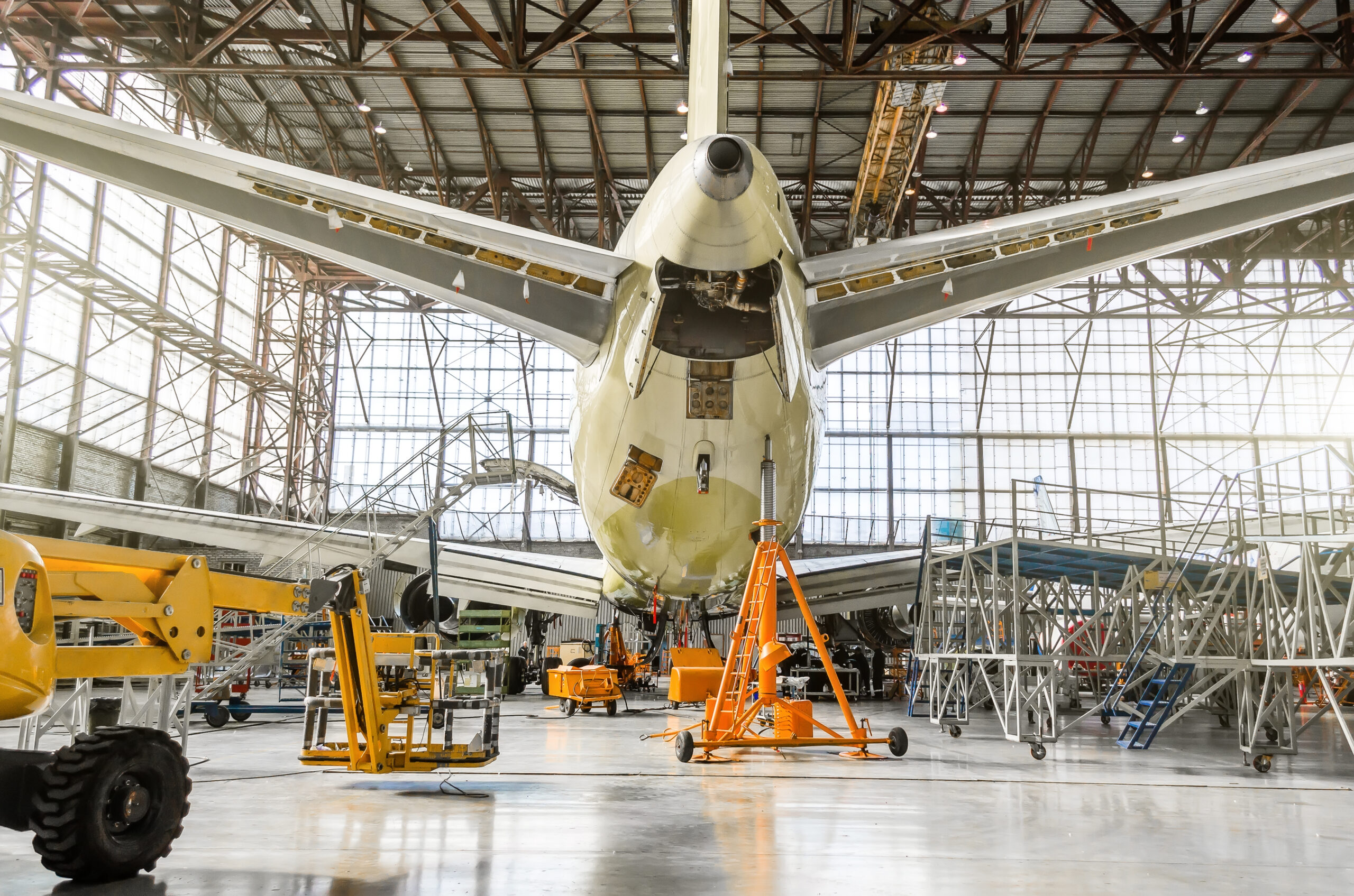 A rear-view of a passenger aircraft undergoing maintenance in a hangar.