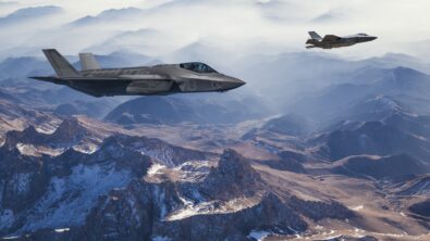 Two fighter jets flying high above a mountainous landscape.