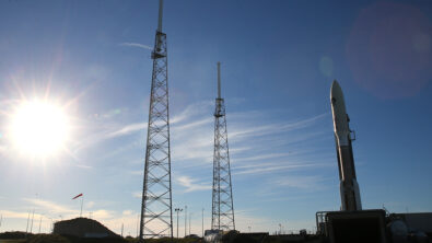 A rocket standing on a launchpad as the sun rises.