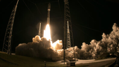 A rocket launching up from a launchpad at night.