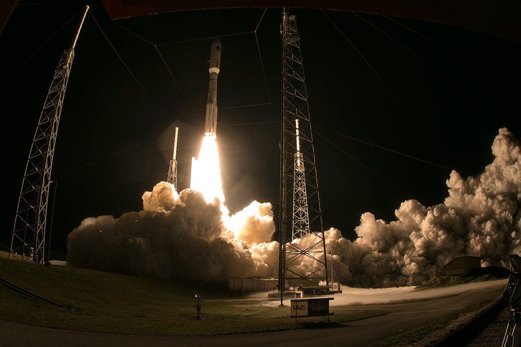 A rocket launching up from a launchpad at night.