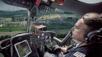 A man piloting a helicopter inside the cockpit.