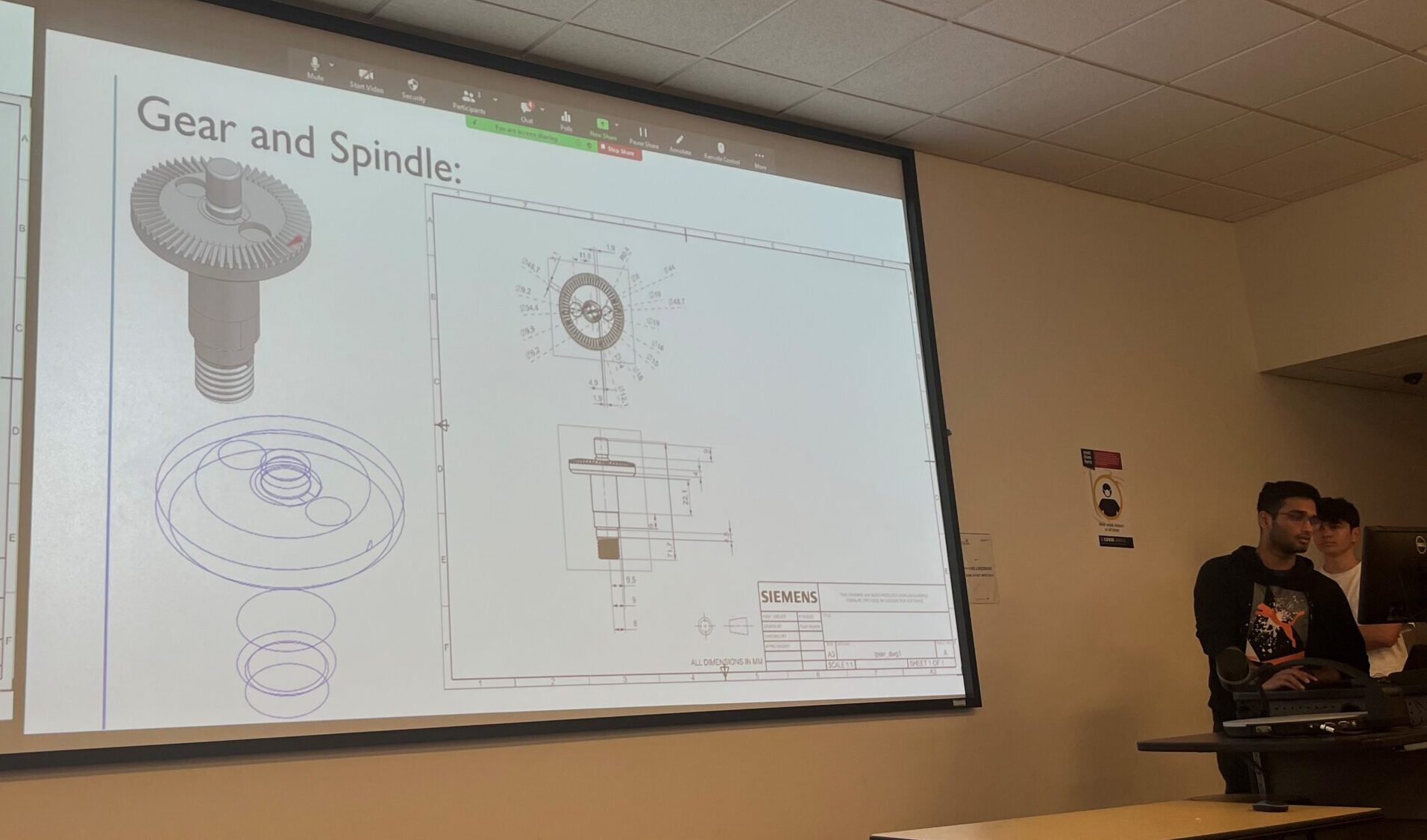 Student presenting a slide of a gear and spindle design in NX, with both the 3D model and the 2D sketch lines.