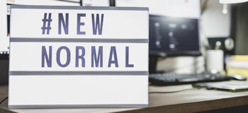 Light signs with text hashtag #NEW NORMAL on the working desk. Work from home. New normal concept. Social distancing.