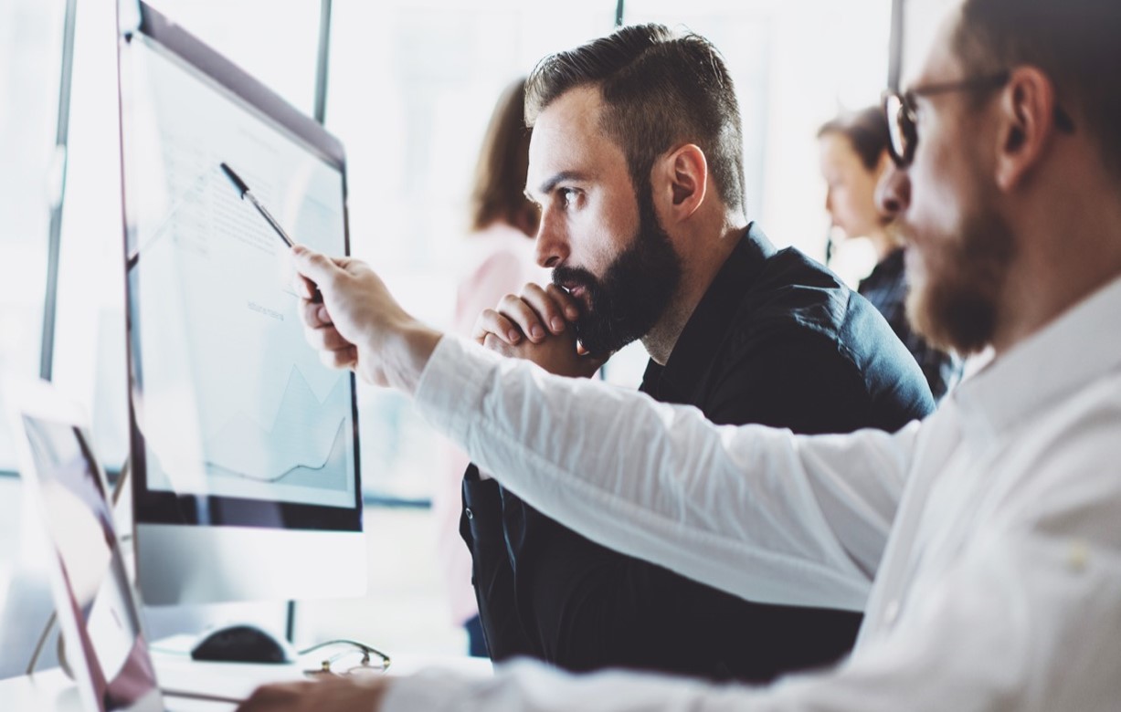 two men looking at a computer screen evaluating scheduling and planning