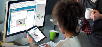 woman looking at tablet and monitor of teamcenter