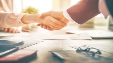 man and woman shaking hands over a conference table