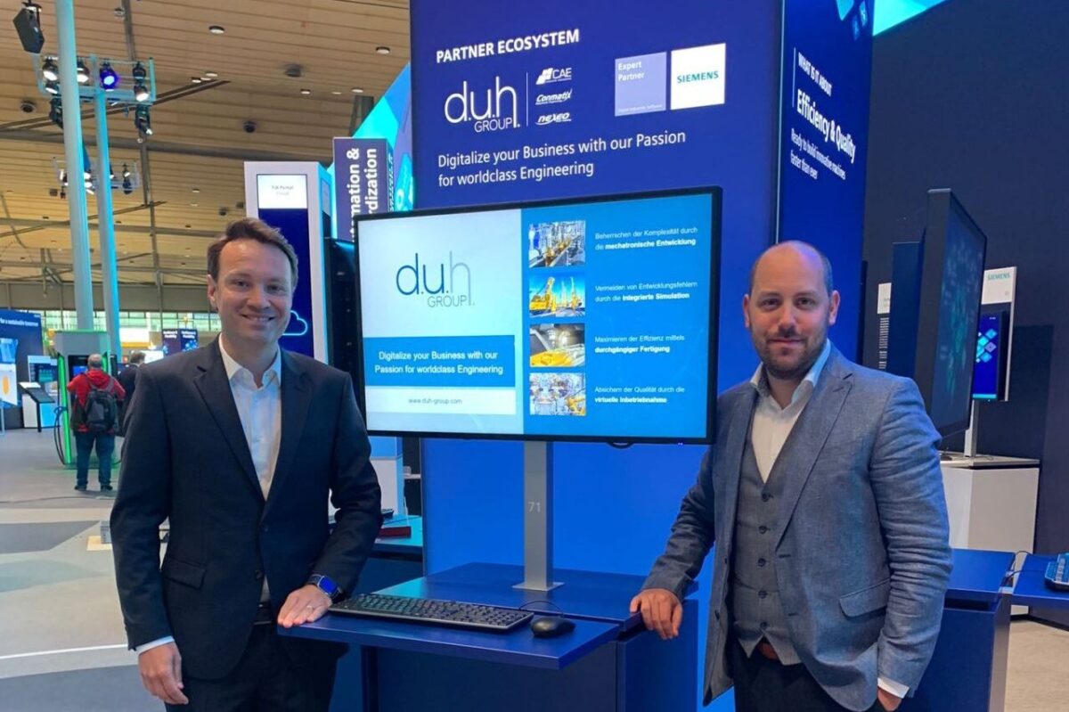 Two men stand in front of a computer at Hannover Messe 2022