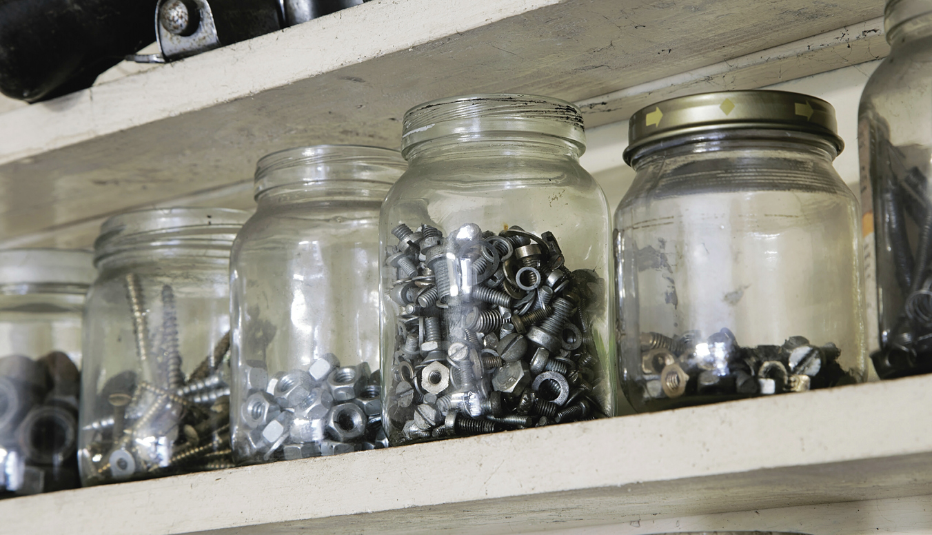 A shelf holding several jars of nuts, bolts and screws. Searching for parts can be a cumbersome and time-consuming, like sifting through jars of old bolts looking for the right one.