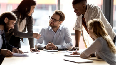 A professional services team collaborates around a table in an office.