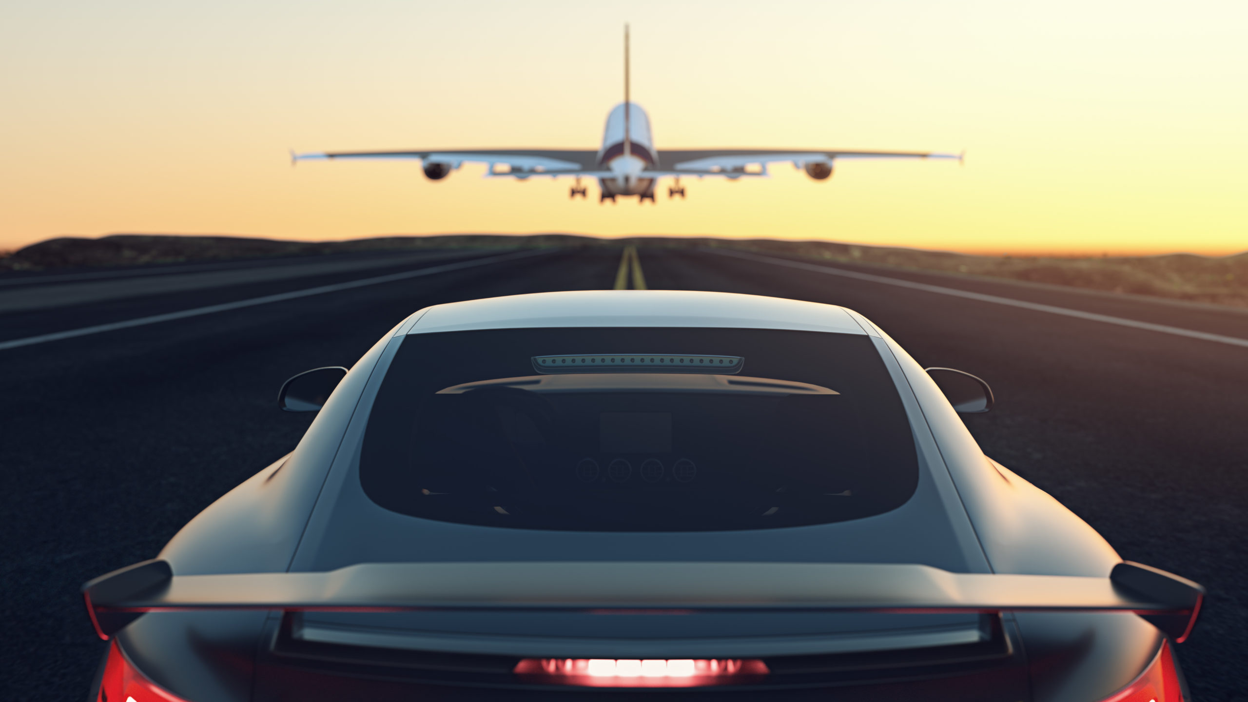 Black and gray luxury car chases airplane down stripped runway into the yellow and orange sunset. This relates to E/E Systems Development and Electrical Systems with Capital by encapsulating both the Aerospace and Automotive industry into one image as well as how we are continually moving forward with solutions for our customers.