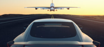 Black and gray luxury car chases airplane down stripped runway into the yellow and orange sunset. This relates to E/E Systems Development and Electrical Systems with Capital by encapsulating both the Aerospace and Automotive industry into one image as well as how we are continually moving forward with solutions for our customers. E/E Systems industry articles automotive aerospace