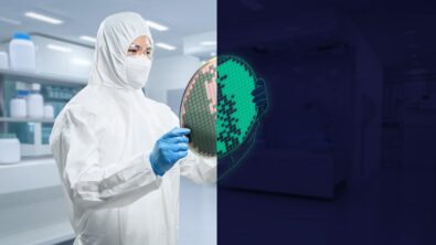 The image shows a person in a protective white full-body suit, including a hood and mask, holding a green silicon wafer with etched patterns in what appears to be a high-tech manufacturing facility or cleanroom environment. The background is slightly blurred, but displays a futuristic-looking interior space with bright overhead lighting. The image's focus and composition highlights the worker inspecting or presenting the silicon wafer, which is a key component used in semiconductor and microchip production.