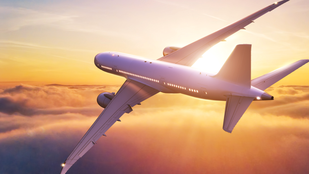 a commercial airplane flies through the sky as the sun sets in the background