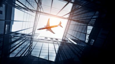 an airplane is seen flying overhead between tall buildings