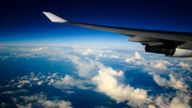 The wing of an airplane is seen against a vibrant blue sky and fluffy white clouds