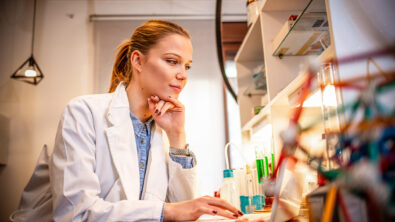 Female engineer wearing lab coat looking at computer of a medical device design