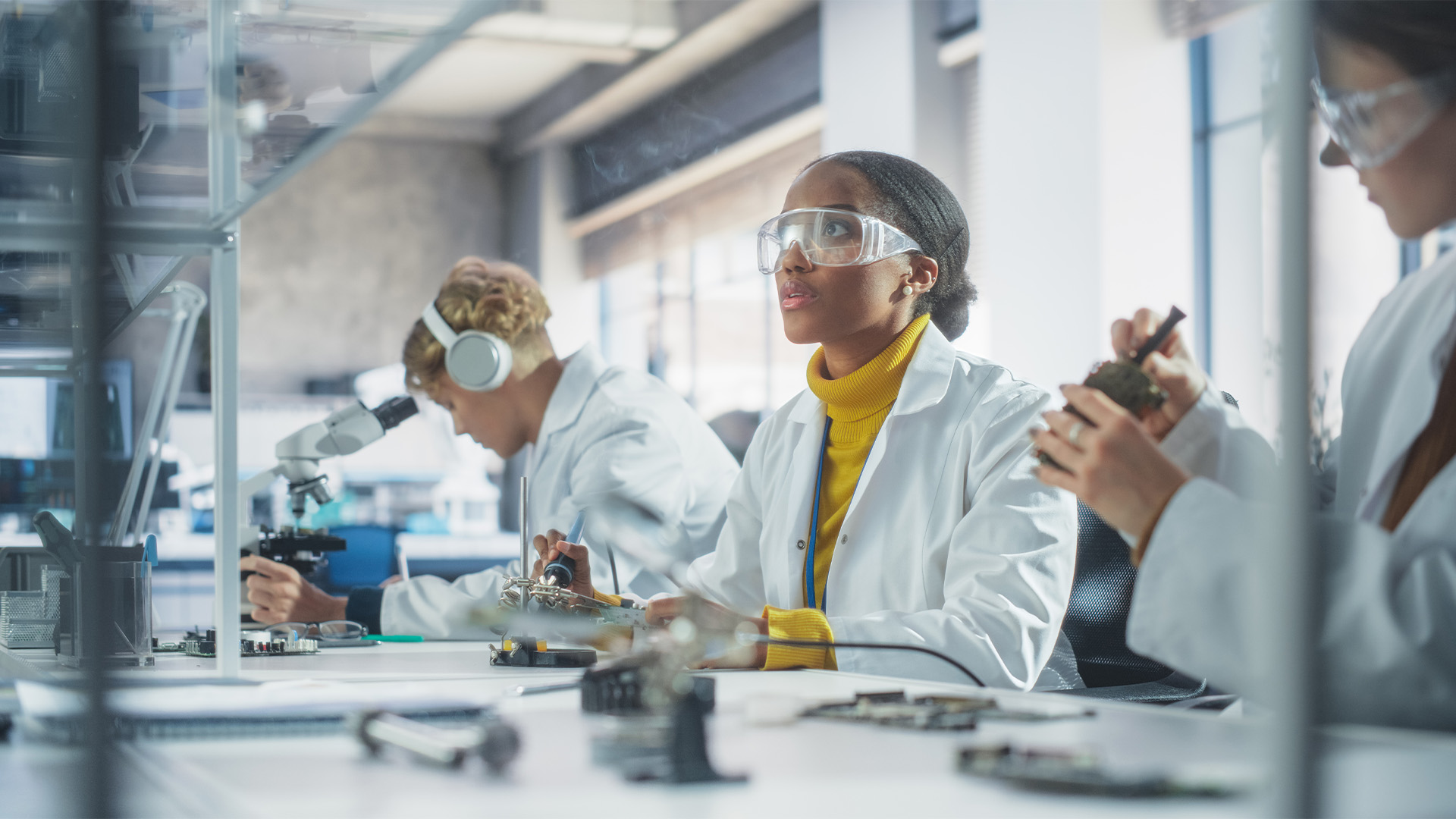 Three engineers wearing protective eye gear looking at a computer.