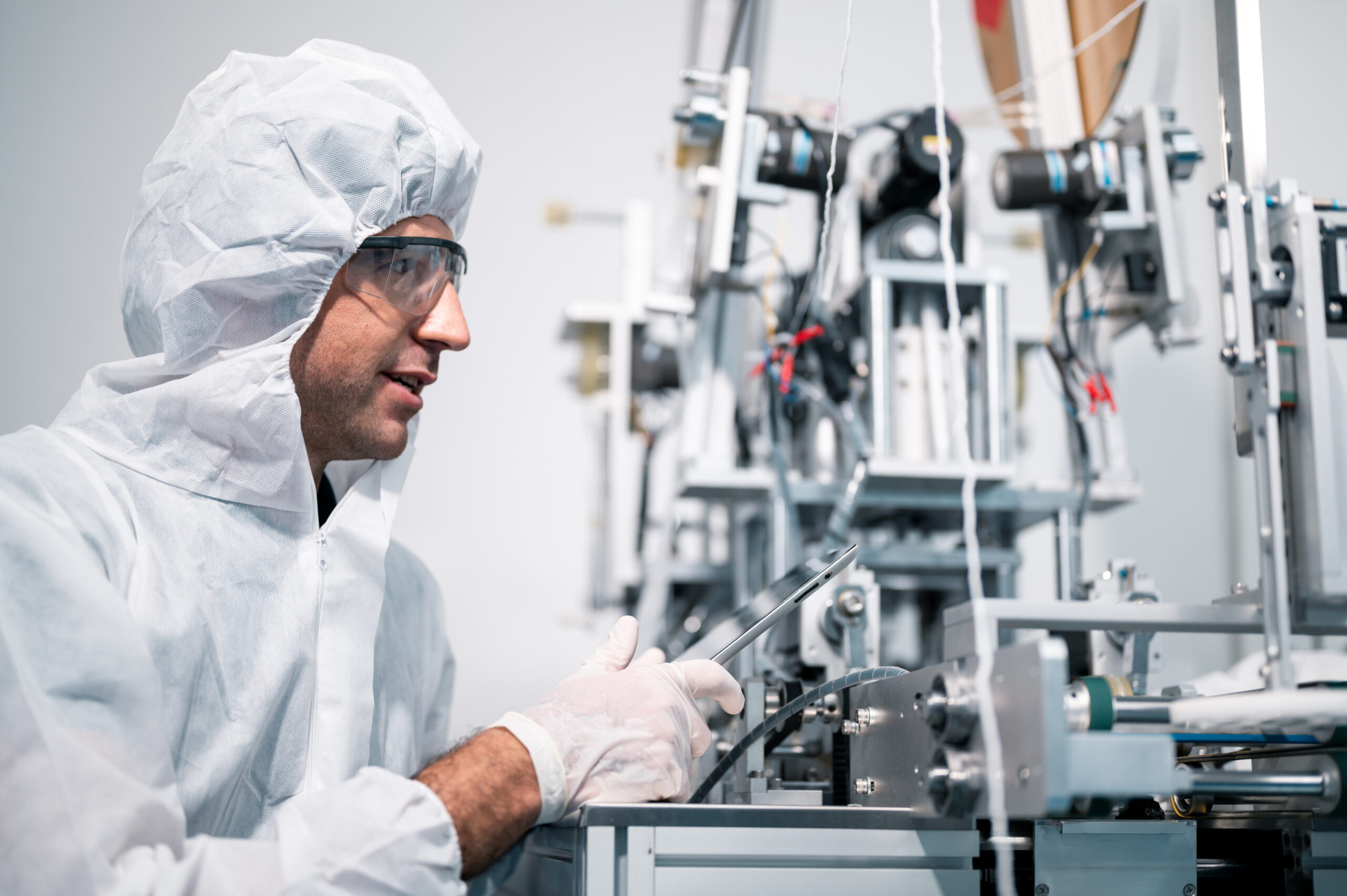 Scientist wearing protective clothing working on a machine in a medical device manufacturing facility.