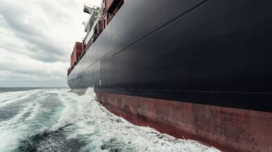 A side view of a cargo ship sailing through the ocean.