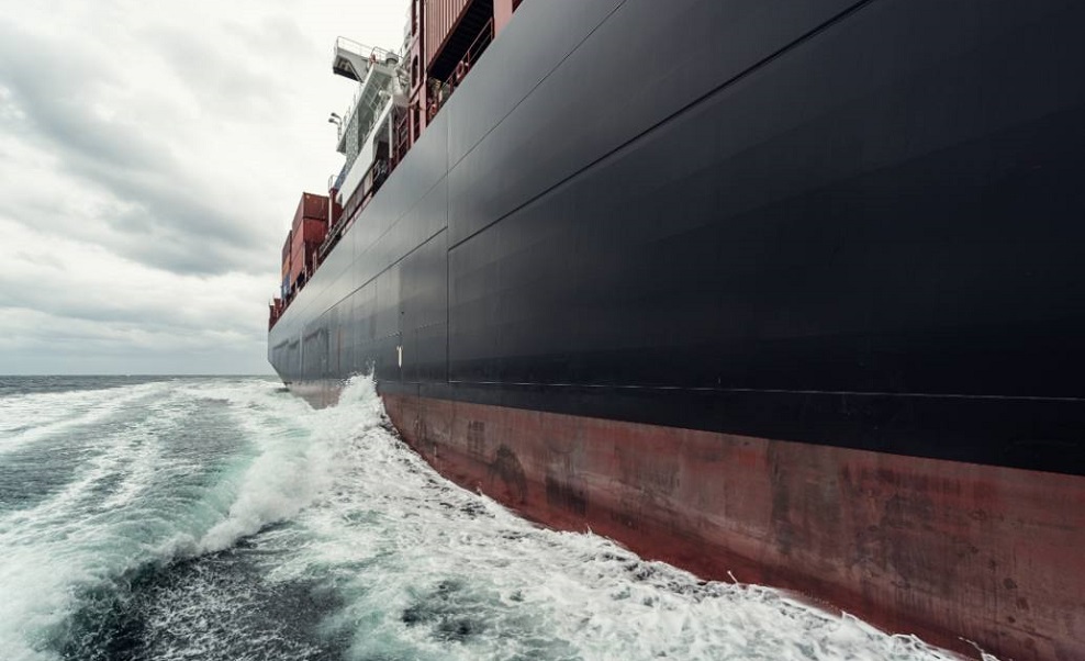 A side view of a cargo ship sailing through the ocean.