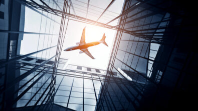 An airplane flying over the skyscrapers of a city, seen from the ground.