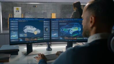 Female and male engineers in experimental crash test laboratory watching process of traffic accident simulation, to get safety parameters of a new electro eco-friendly car body using computer system.