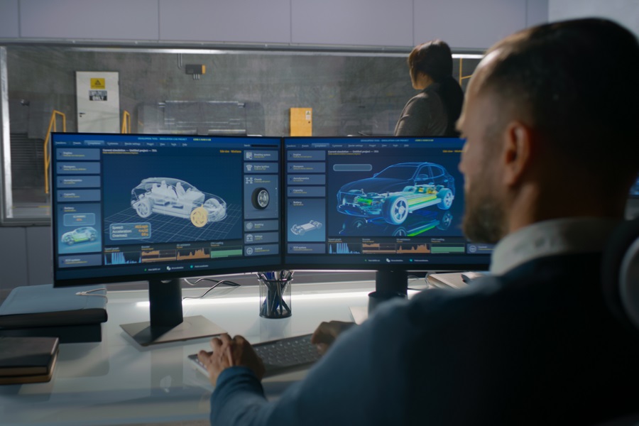 Female and male engineers in experimental crash test laboratory watching process of traffic accident simulation, to get safety parameters of a new electro eco-friendly car body using computer system.