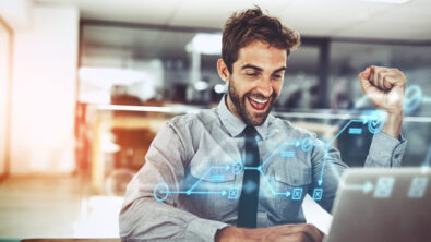 Businessman cheering at his laptop with a fist in the air. There is a digital overlay of a flow chart, representing what is on the computer screen,.