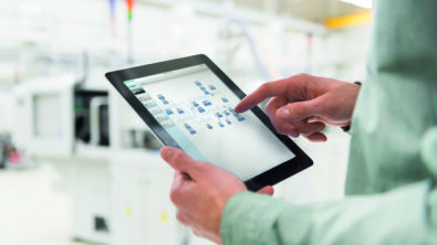 Male worker using digital tablet at tool manufacturing plant, focus on hands