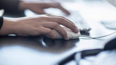 hands of a woman working on a computer and computer mouse