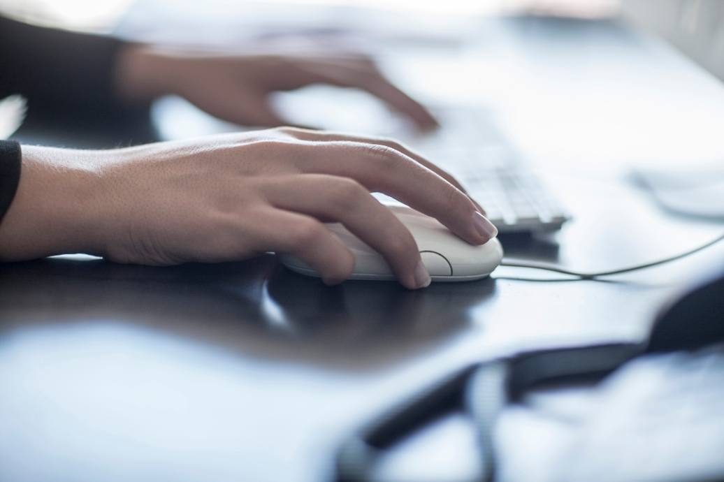 hands of a woman working on a computer and computer mouse