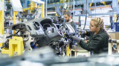 Woman working on a car engine in an automotive manufacting plant