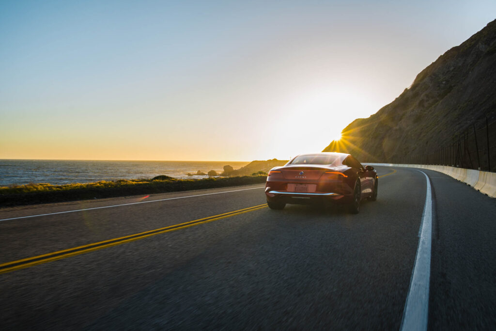 A Karma Revero GT drives towards to the setting sun