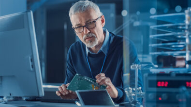 Engineer seated at computer studying physical prototype for early planning of interconnect systems and design verification workflows